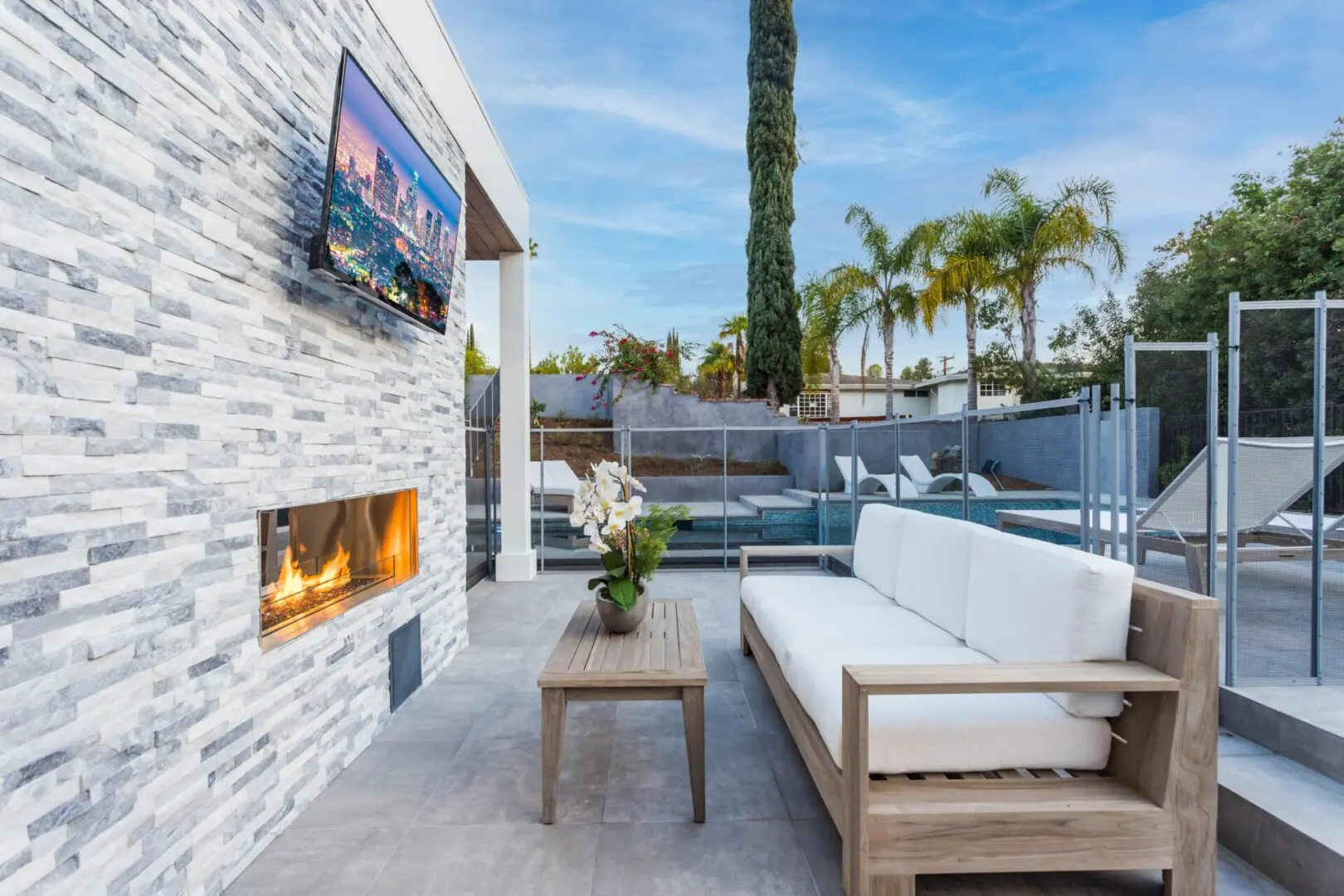 outdoor couch with table and flat screen TV and fireplace