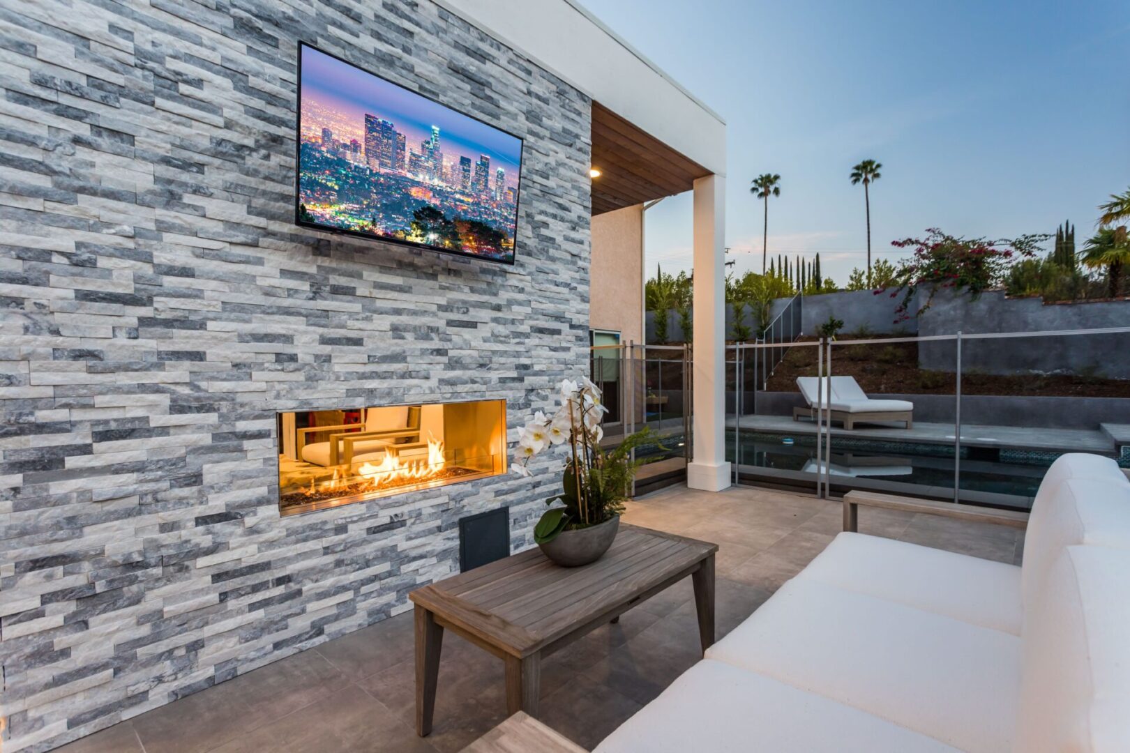 white couch and table with outdoor TV and fireplace